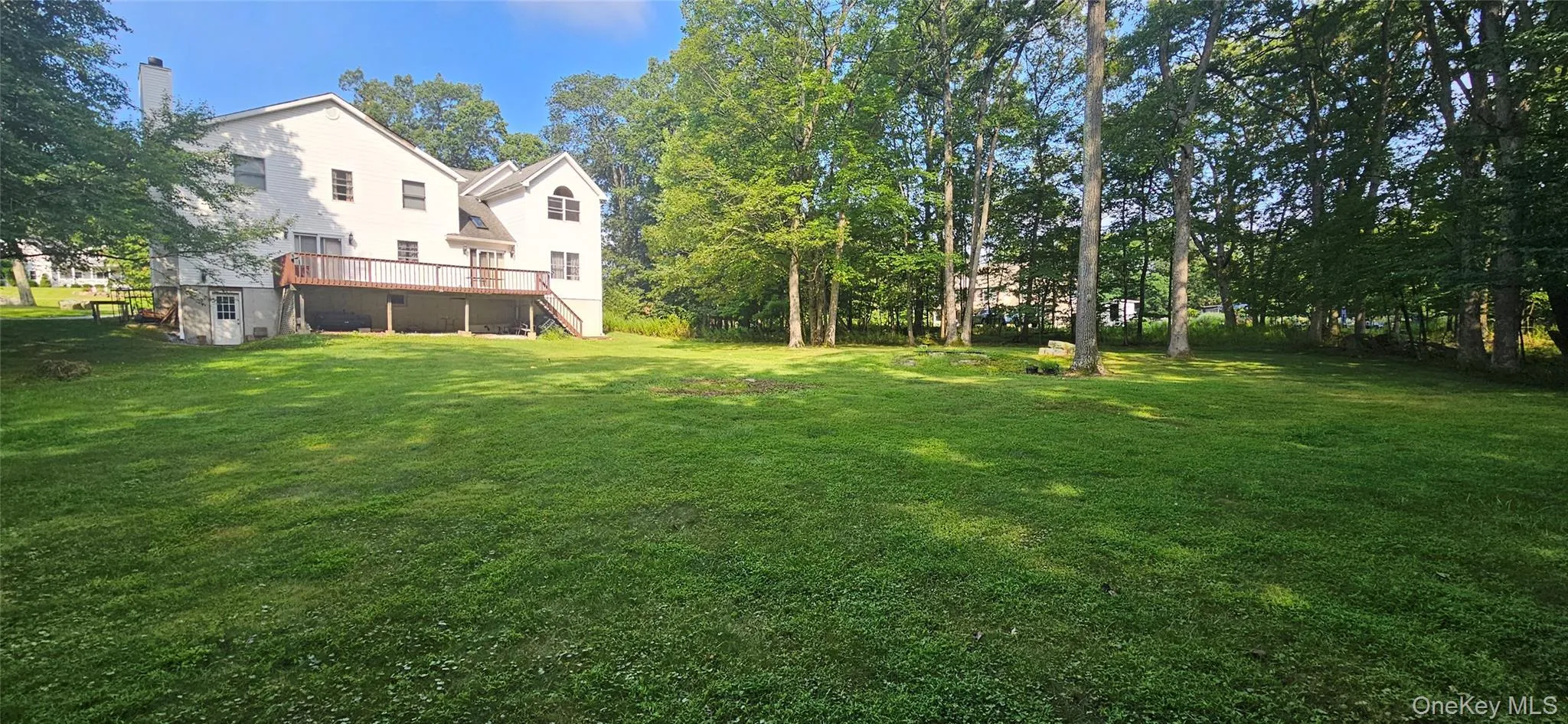 View of green lawn with a wooden deck and stairs View of green lawn with a wooden deck and stairs