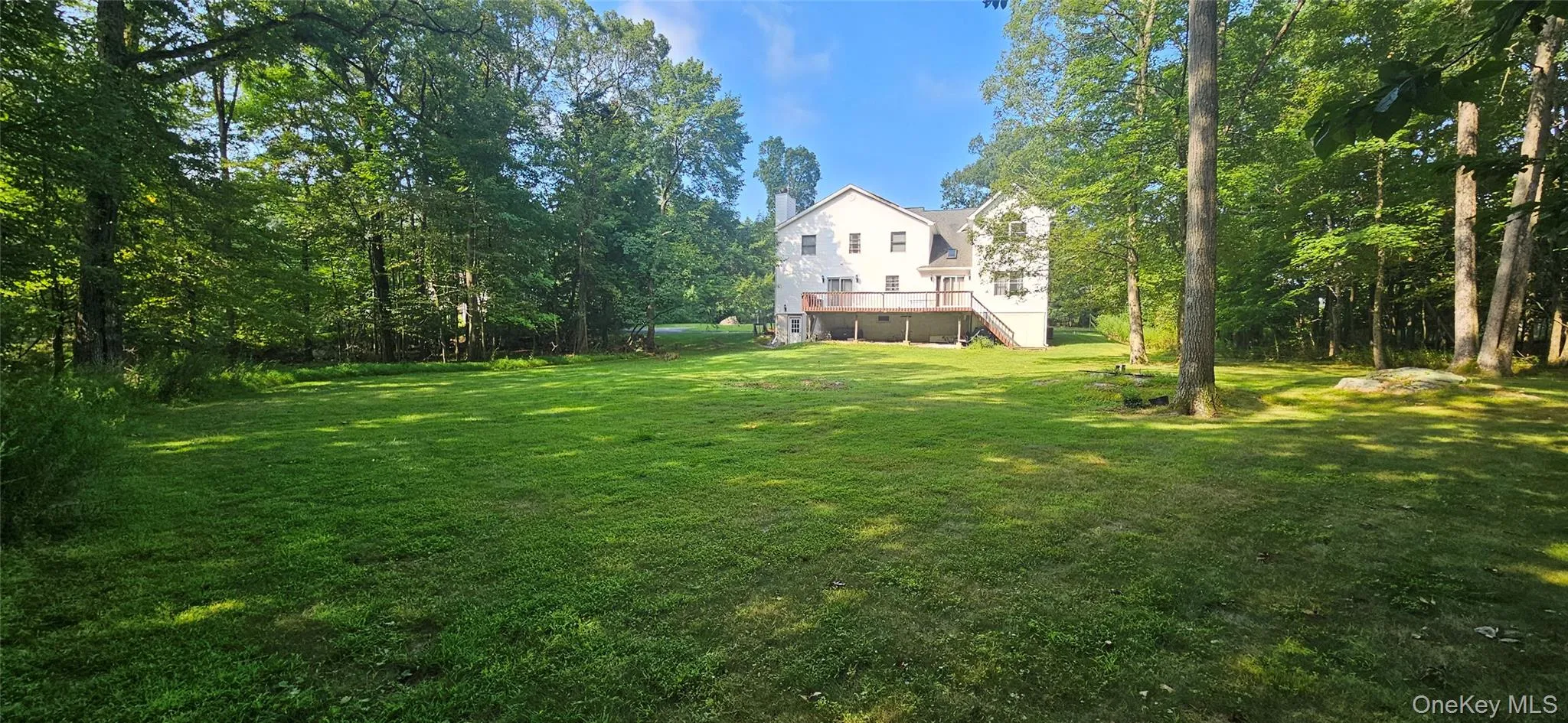 View of grassy yard featuring a deck and stairs View of grassy yard featuring a deck and stairs