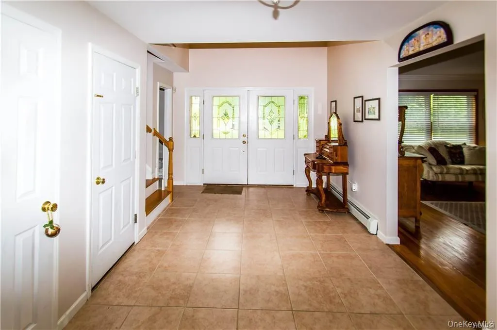 Foyer with light tile patterned floors, stairway, and a baseboard radiator Foyer with light tile patterned floors, stairway, and a baseboard radiator