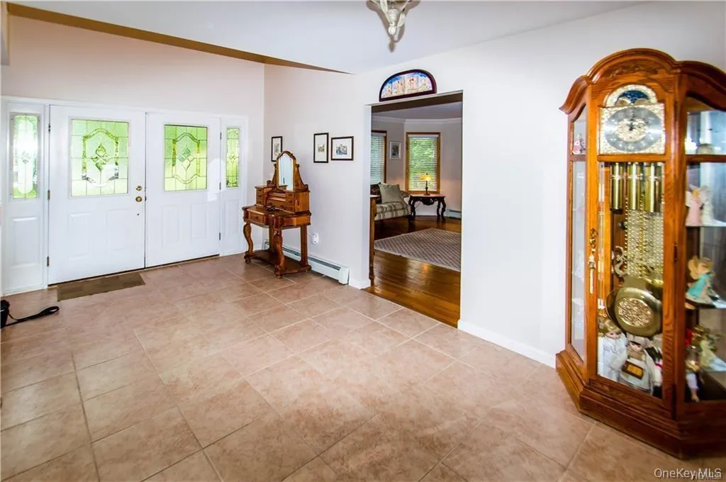 Foyer featuring a baseboard radiator, crown molding, light tile patterned floors, and french doors Foyer featuring a baseboard radiator, crown molding, light tile patterned floors, and french doors