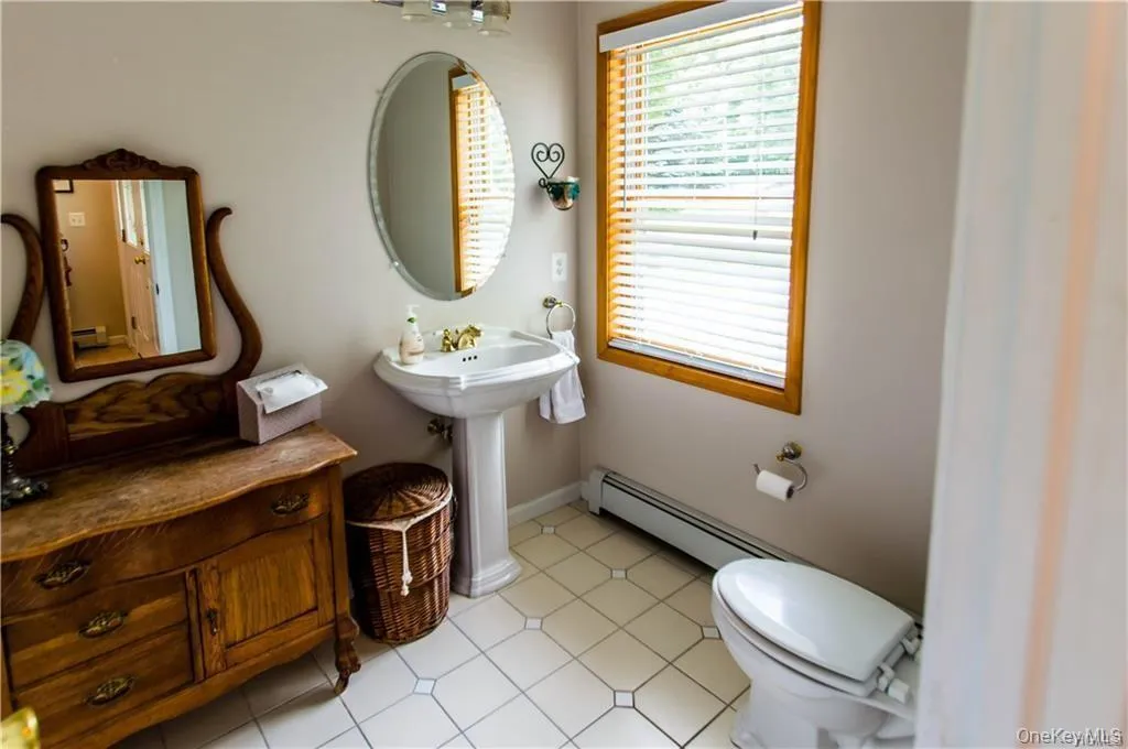 Half bathroom featuring light tile patterned floors and a baseboard heating unit Half bathroom featuring light tile patterned floors and a baseboard heating unit