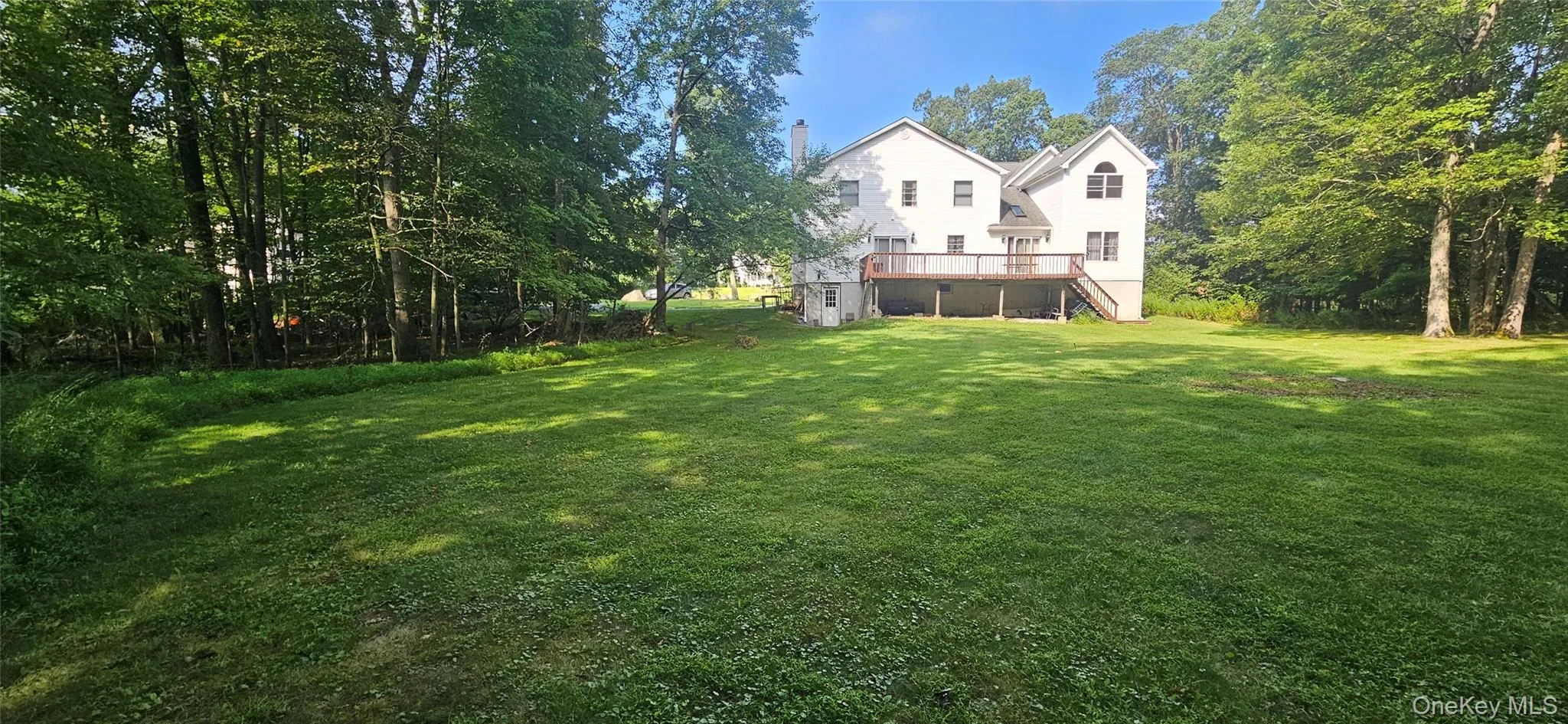 View of grassy yard with a deck and stairs View of grassy yard with a deck and stairs