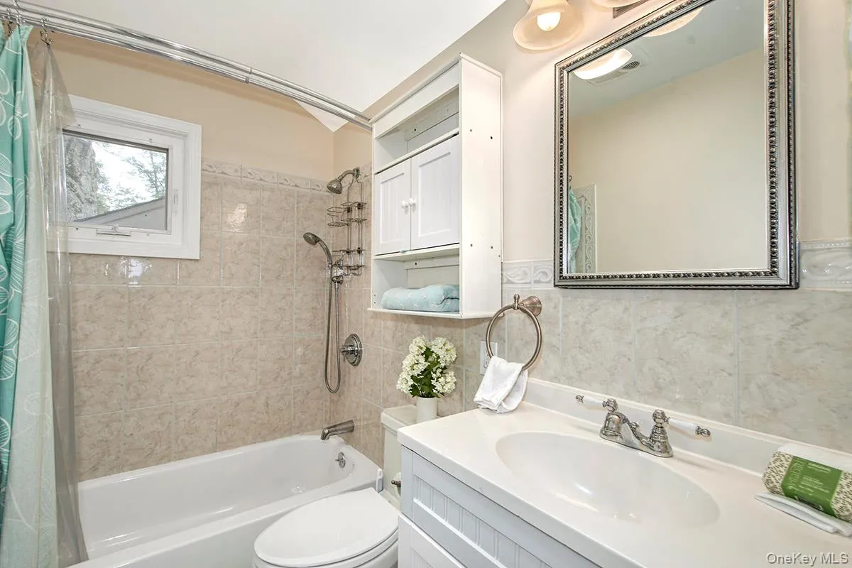 Full bathroom with shower / bath combo with shower curtain, vanity, and tile walls Full bathroom with shower / bath combo with shower curtain, vanity, and tile walls