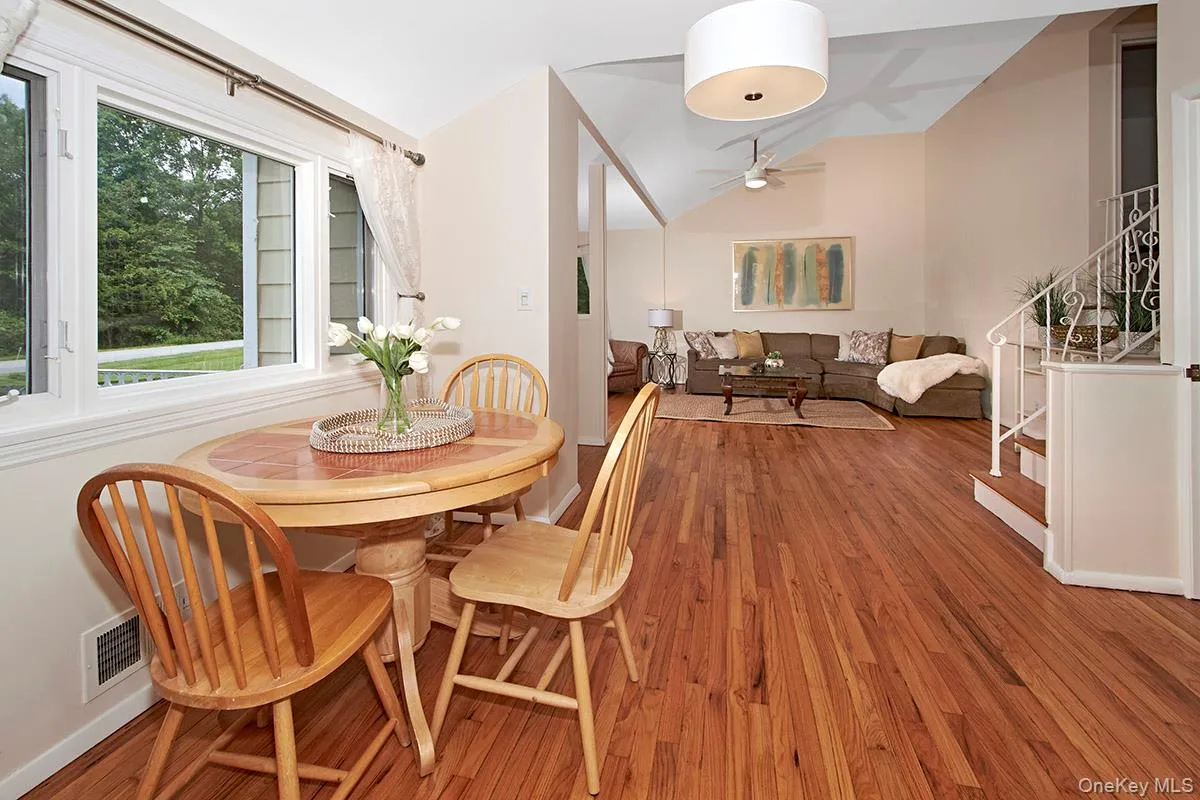 Dining space featuring stairs, lofted ceiling, wood finished floors, and a ceiling fan Dining space featuring stairs, lofted ceiling, wood finished floors, and a ceiling fan