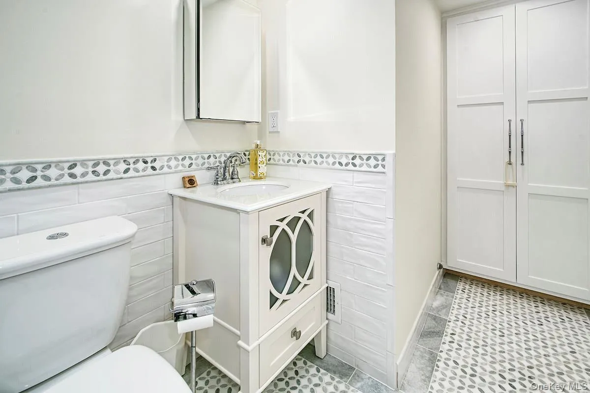 Bathroom featuring a wainscoted wall, vanity, tile walls, and light tile patterned floors Bathroom featuring a wainscoted wall, vanity, tile walls, and light tile patterned floors