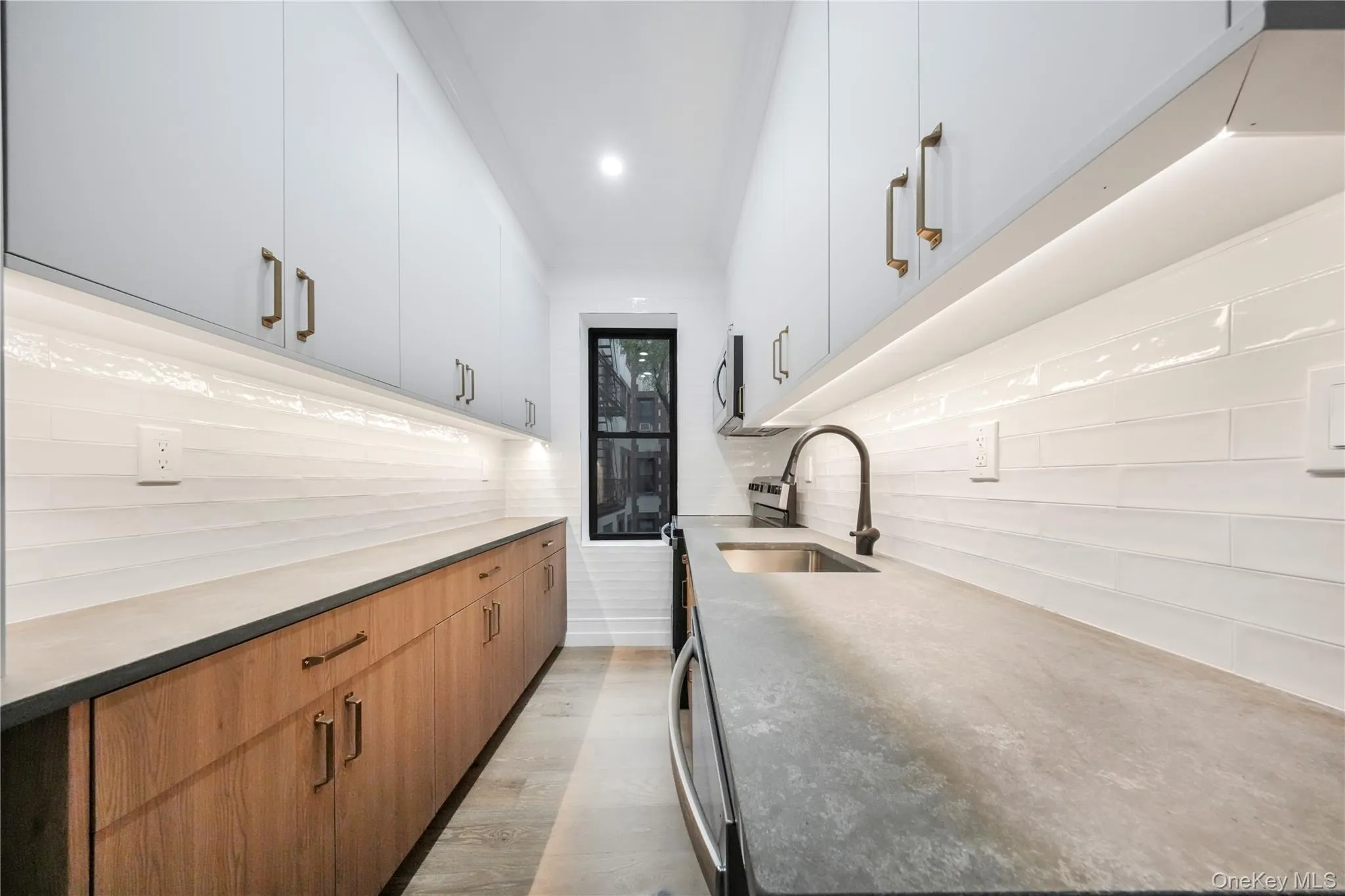 Kitchen with stove, brown cabinetry, light wood-style floors, modern cabinets, and light stone countertops Kitchen with stove, brown cabinetry, light wood-style floors, modern cabinets, and light stone countertops