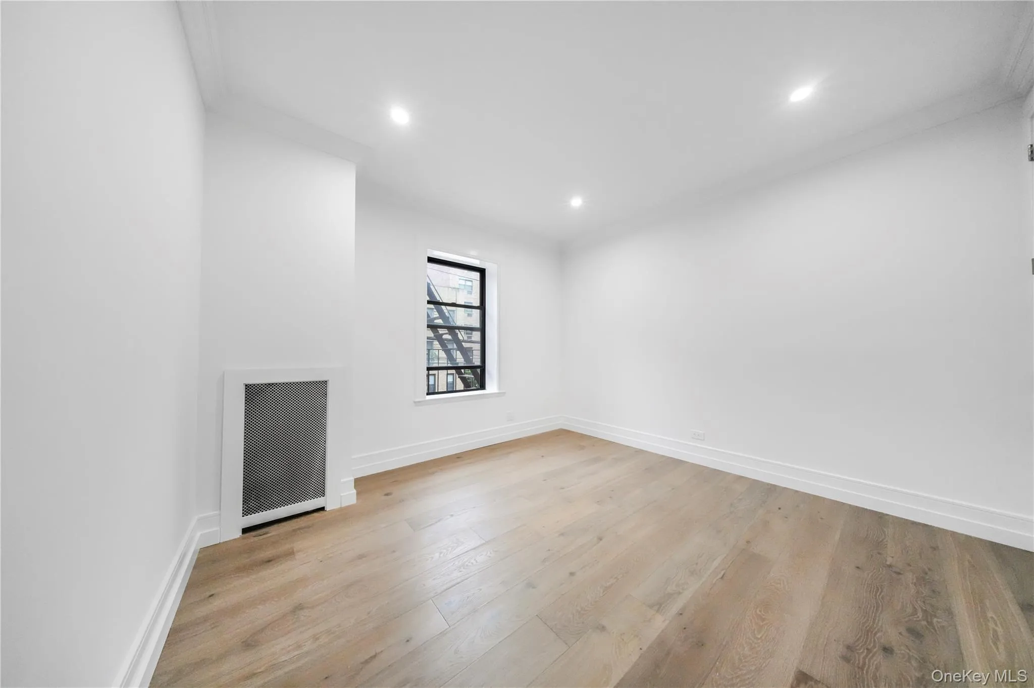 Spare room featuring light wood-style flooring, recessed lighting, ornamental molding, and radiator heating unit Spare room featuring light wood-style flooring, recessed lighting, ornamental molding, and radiator heating unit