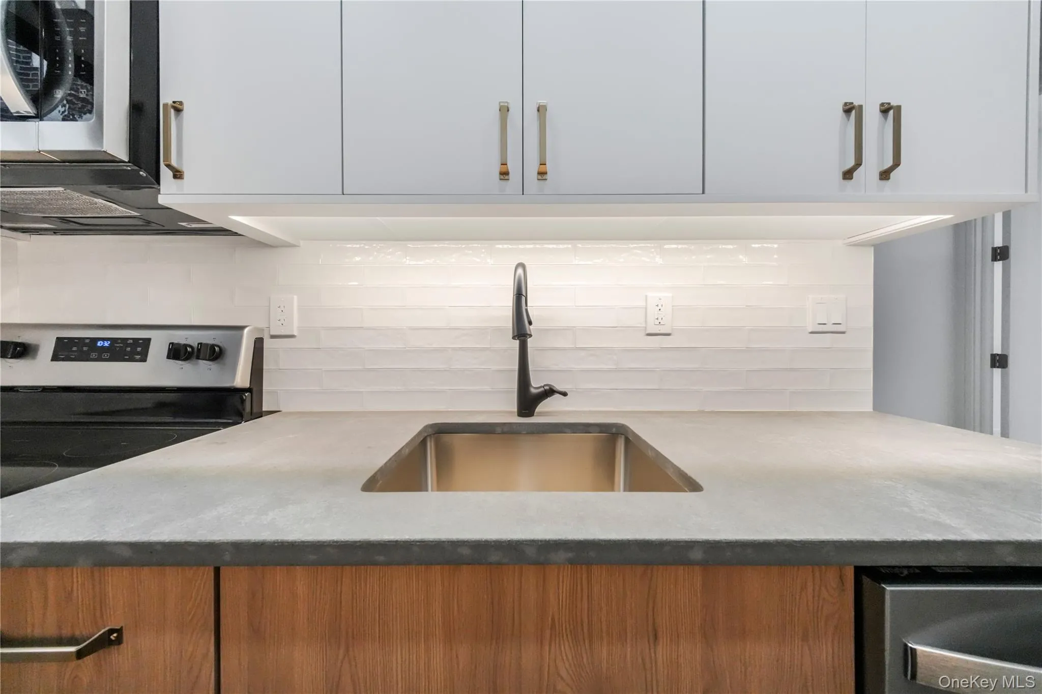 Kitchen with decorative backsplash, light stone countertops, and electric range Kitchen with decorative backsplash, light stone countertops, and electric range