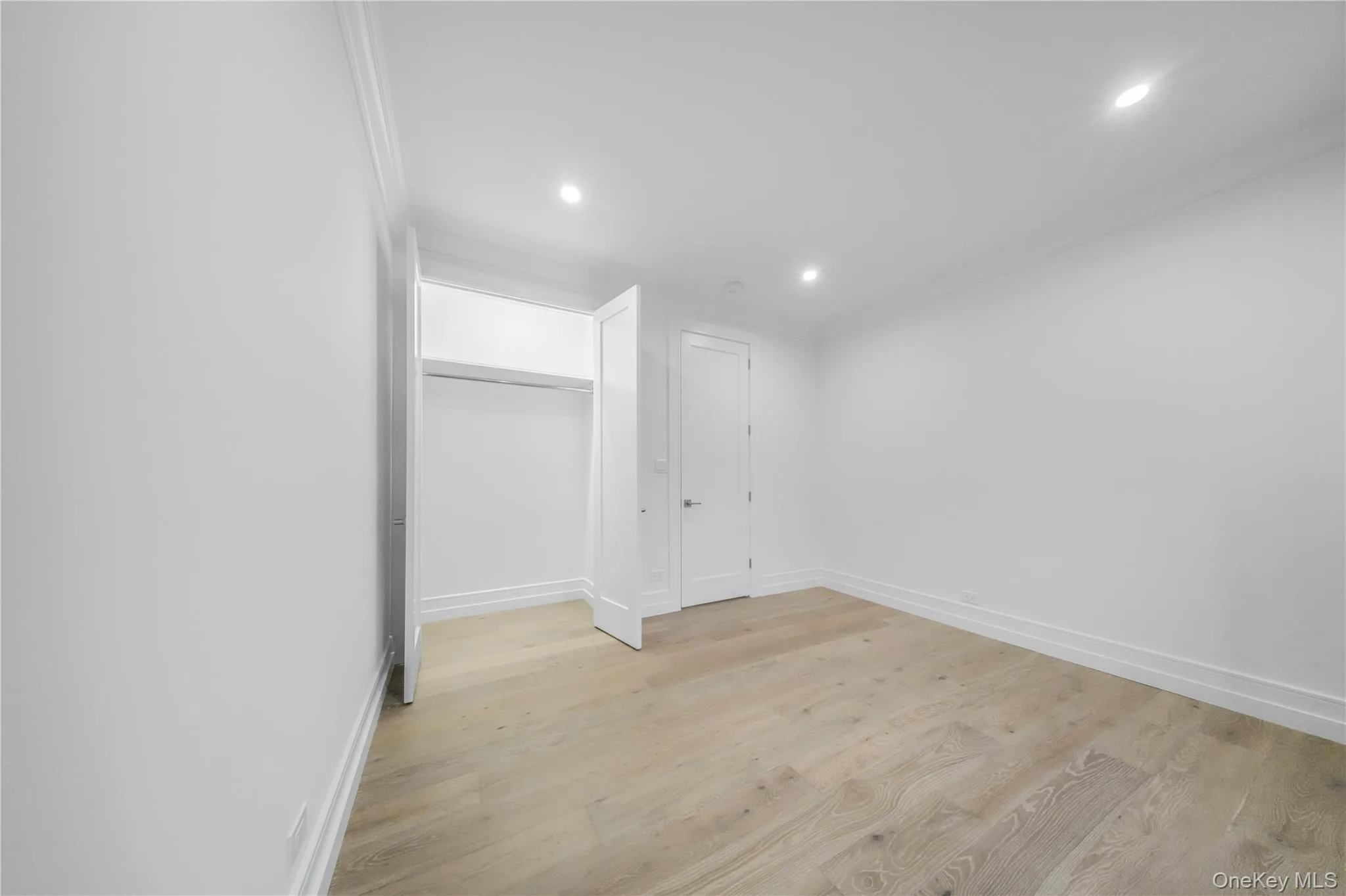 Unfurnished bedroom with light wood-style floors, recessed lighting, crown molding, and a closet Unfurnished bedroom with light wood-style floors, recessed lighting, crown molding, and a closet