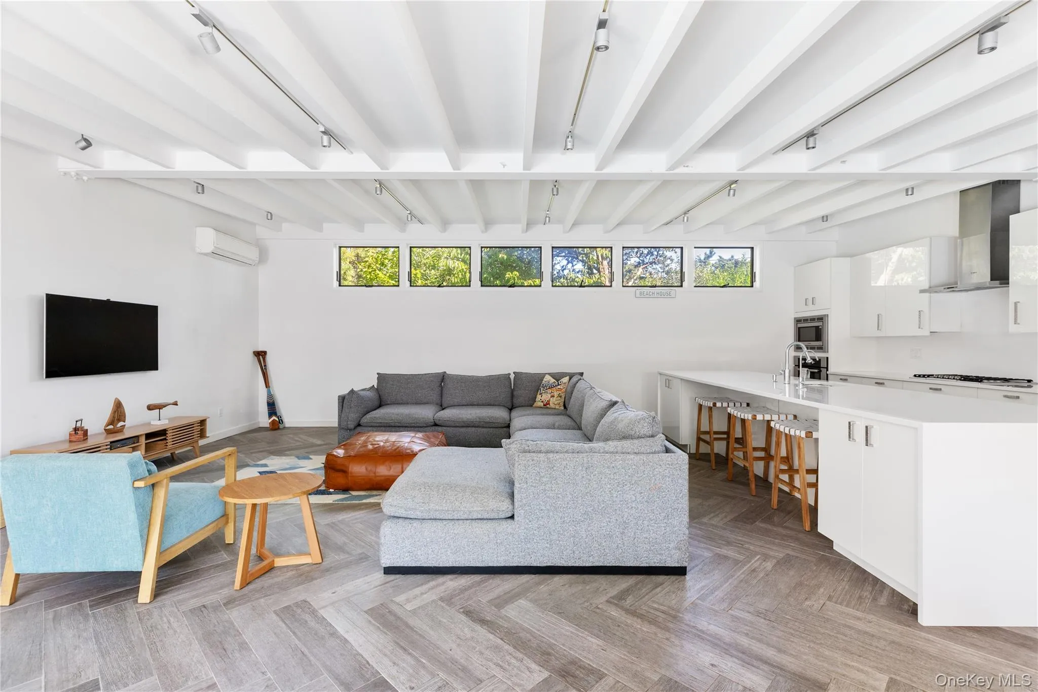 Living room with beam ceiling, track lighting, and an AC wall unit Living room with beam ceiling, track lighting, and an AC wall unit