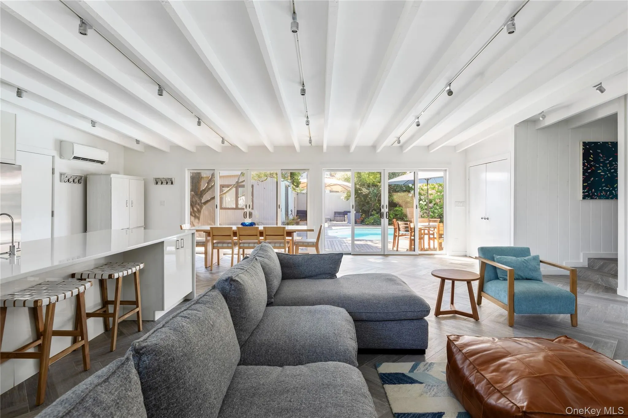 Living area featuring beam ceiling, track lighting, and a wall unit AC Living area featuring beam ceiling, track lighting, and a wall unit AC