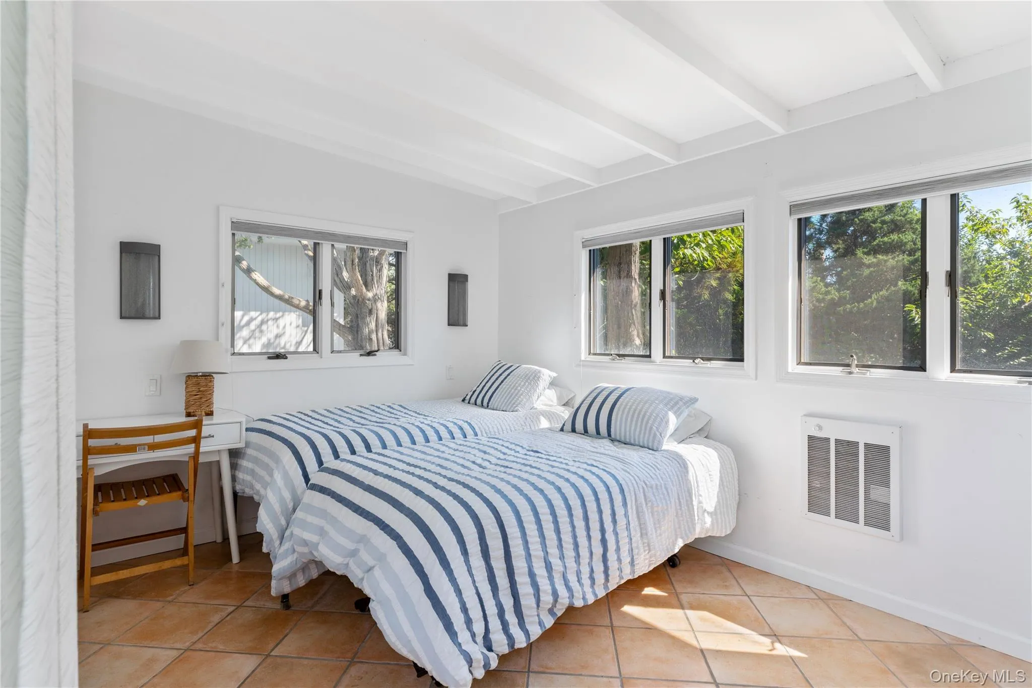 Bedroom featuring light tile patterned floors, heating unit, and beam ceiling Bedroom featuring light tile patterned floors, heating unit, and beam ceiling