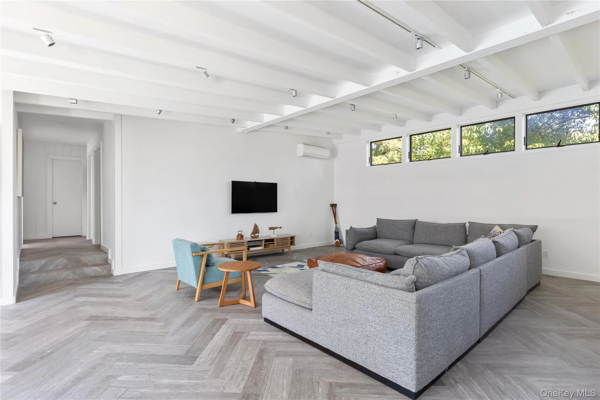 Living room featuring beamed ceiling, track lighting, and a wall mounted AC Living room featuring beamed ceiling, track lighting, and a wall mounted AC