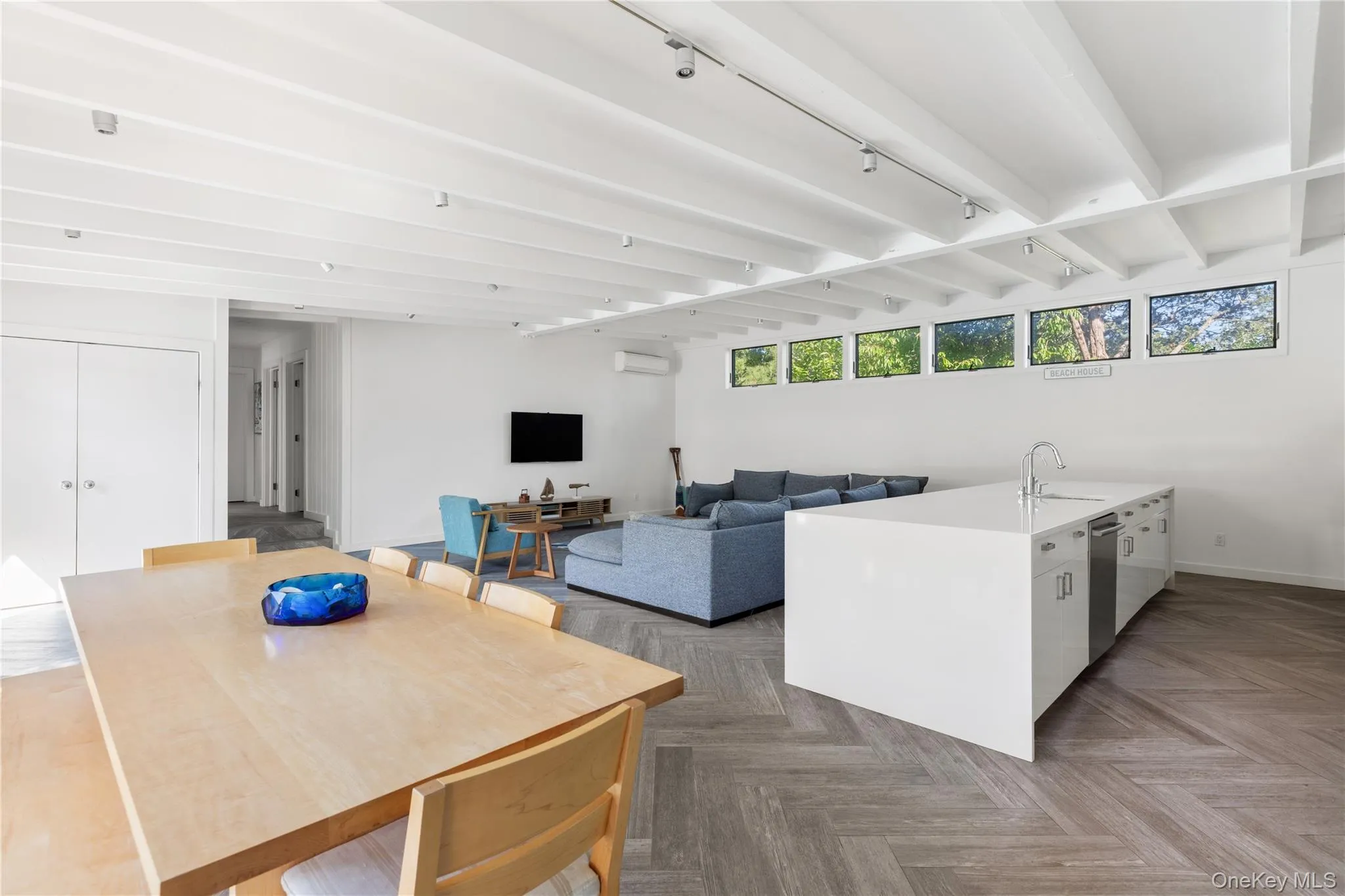 Kitchen featuring white cabinetry, beam ceiling, light stone countertops, stainless steel dishwasher, and modern cabinets Kitchen featuring white cabinetry, beam ceiling, light stone countertops, stainless steel dishwasher, and modern cabinets