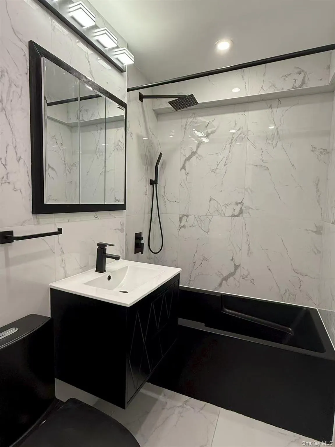 Bathroom with light marble finish floors, stone wall, tile walls, vanity, and a marble finish shower Bathroom with light marble finish floors, stone wall, tile walls, vanity, and a marble finish shower