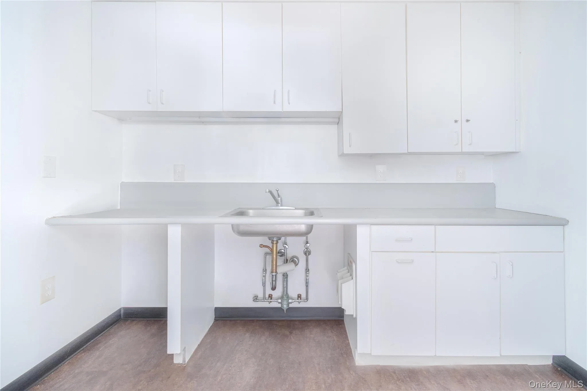 Kitchen with light countertops, white cabinets, and wood finished floors Kitchen with light countertops, white cabinets, and wood finished floors