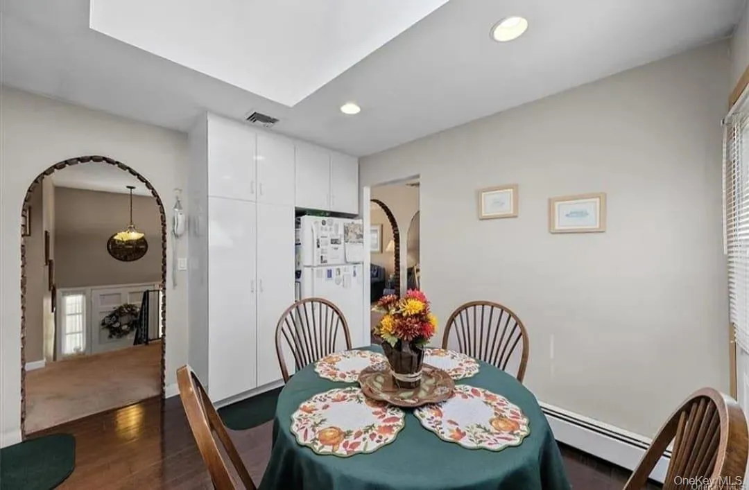 Dining space with arched walkways, dark wood-style floors, a baseboard heating unit, and recessed lighting Dining space with arched walkways, dark wood-style floors, a baseboard heating unit, and recessed lighting