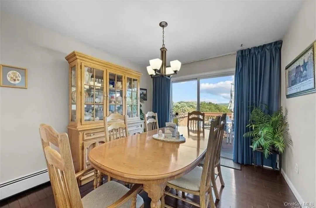 Dining space featuring dark wood-style flooring, a chandelier, and a baseboard heating unit Dining space featuring dark wood-style flooring, a chandelier, and a baseboard heating unit