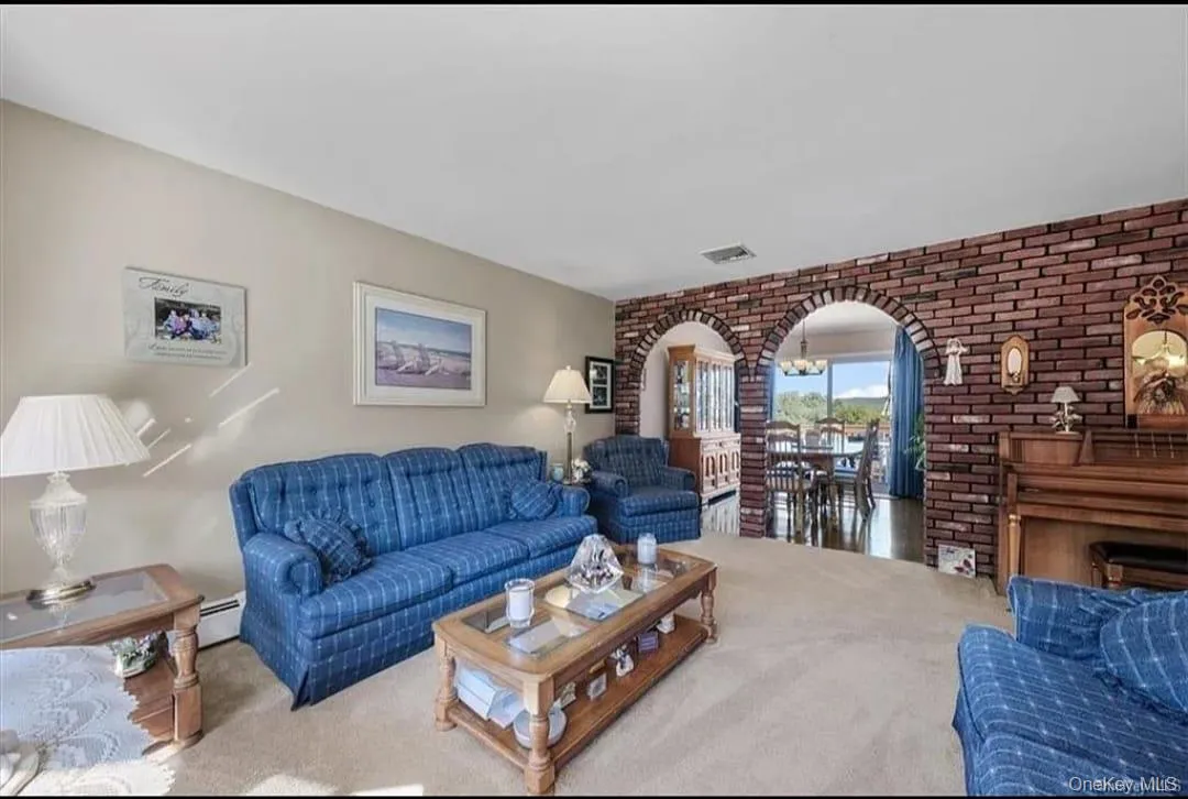 Living area with arched walkways, carpet, brick wall, and a baseboard radiator Living area with arched walkways, carpet, brick wall, and a baseboard radiator