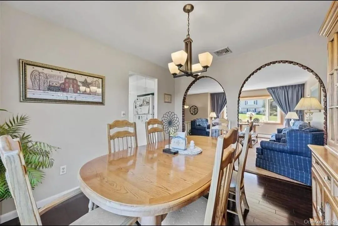 Dining space with dark wood-type flooring and a chandelier Dining space with dark wood-type flooring and a chandelier