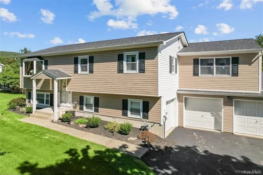 Bi-level home featuring asphalt driveway, an attached garage, and a front lawn Bi-level home featuring asphalt driveway, an attached garage, and a front lawn