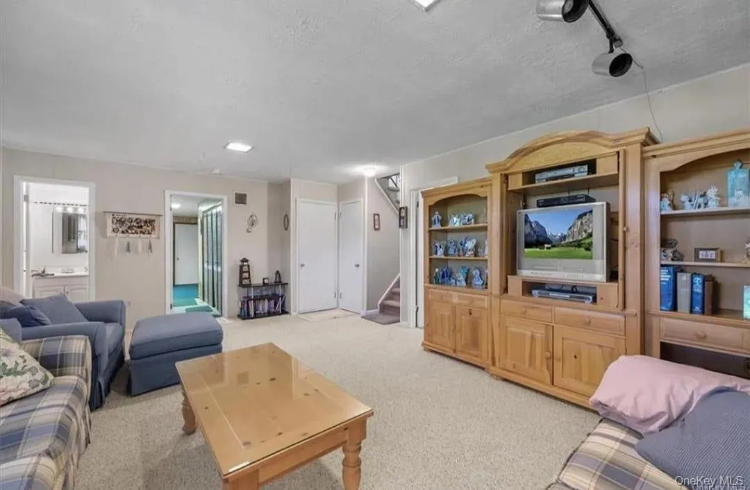 Living area with light carpet, stairway, and a textured ceiling Living area with light carpet, stairway, and a textured ceiling