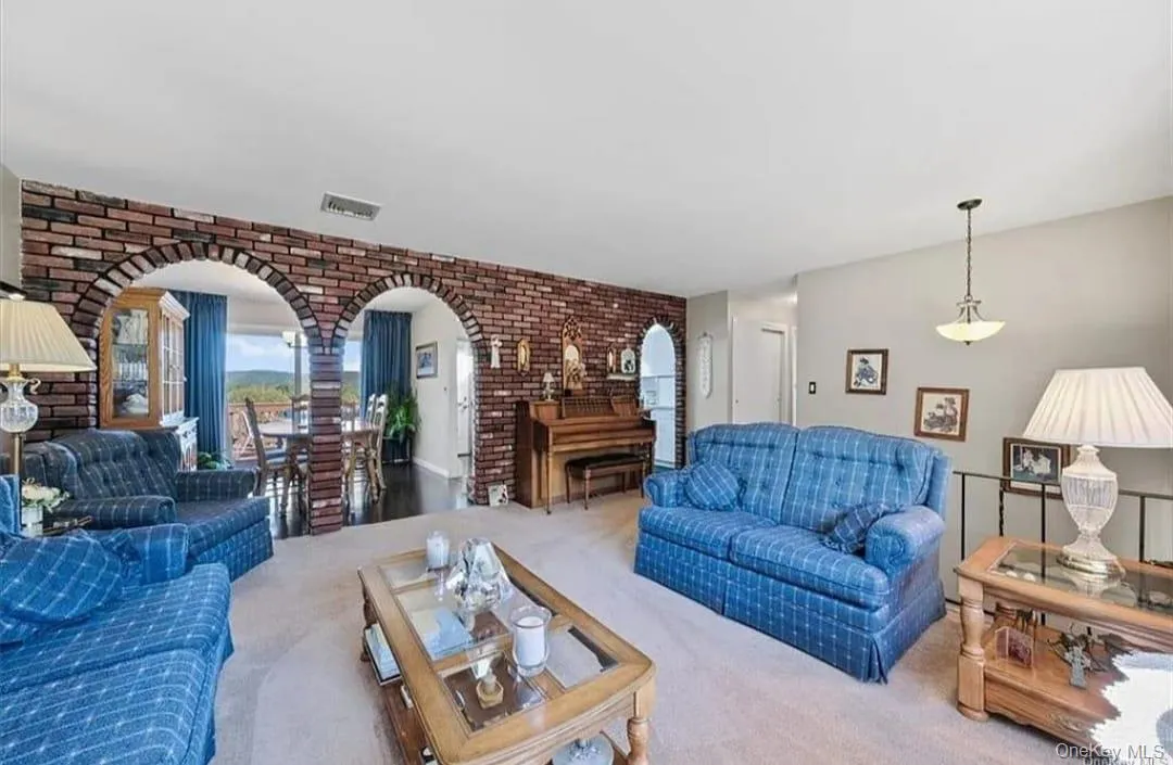 Carpeted living room with arched walkways and brick wall Carpeted living room with arched walkways and brick wall