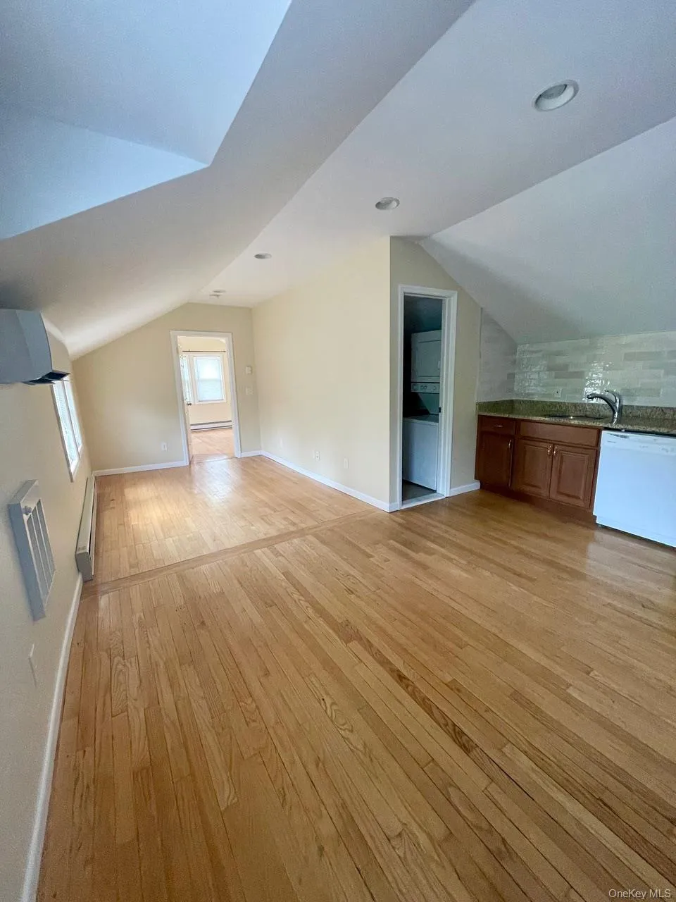 Additional living space with lofted ceiling, light wood-style floors, and washer / clothes dryer Additional living space with lofted ceiling, light wood-style floors, and washer / clothes dryer