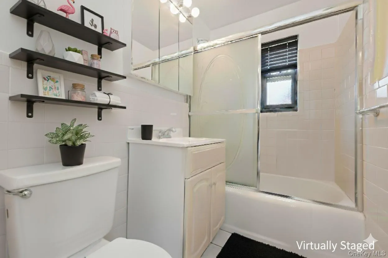 Bathroom featuring vanity, enclosed tub / shower combo, and tile walls Bathroom featuring vanity, enclosed tub / shower combo, and tile walls