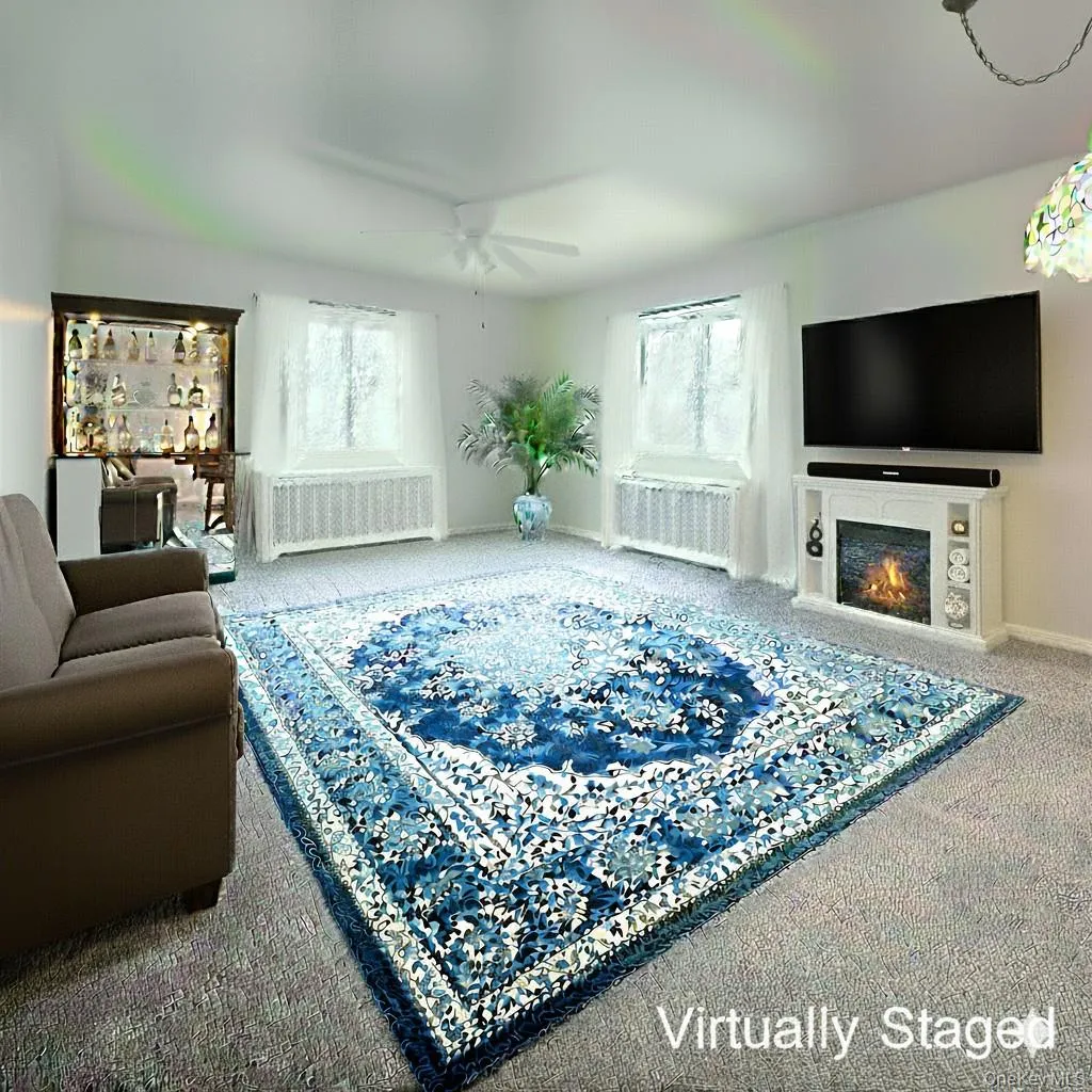 Living area with carpet floors, a warm lit fireplace, radiator, and ceiling fan Living area with carpet floors, a warm lit fireplace, radiator, and ceiling fan