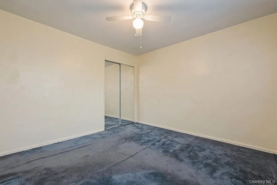 Carpeted empty room with baseboards and ceiling fan Carpeted empty room with baseboards and ceiling fan