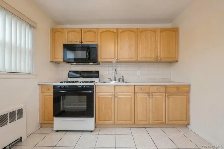 Kitchen featuring gas range oven, light countertops, and decorative backsplash Kitchen featuring gas range oven, light countertops, and decorative backsplash