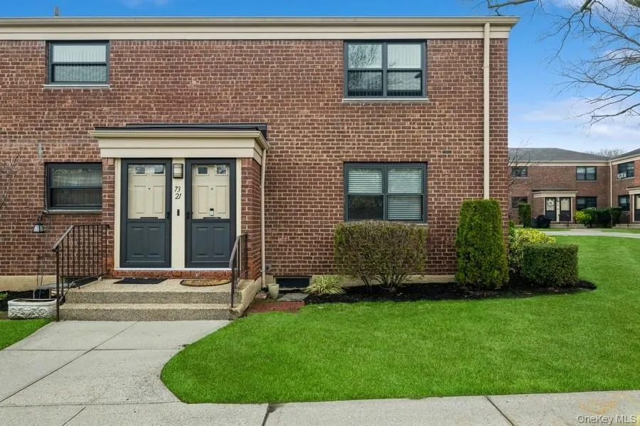 Entrance to property featuring brick siding and a yard Entrance to property featuring brick siding and a yard