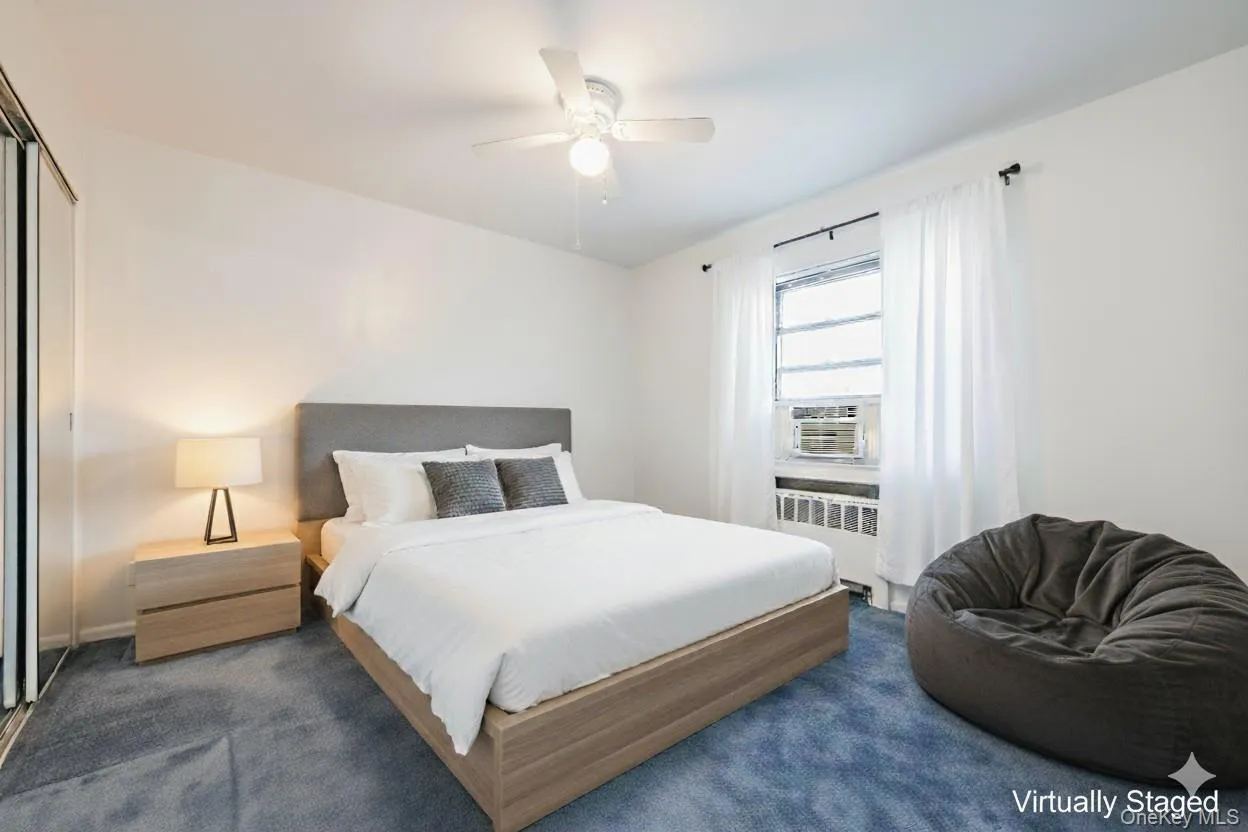 Carpeted bedroom featuring a ceiling fan, radiator, a closet, and cooling unit Carpeted bedroom featuring a ceiling fan, radiator, a closet, and cooling unit