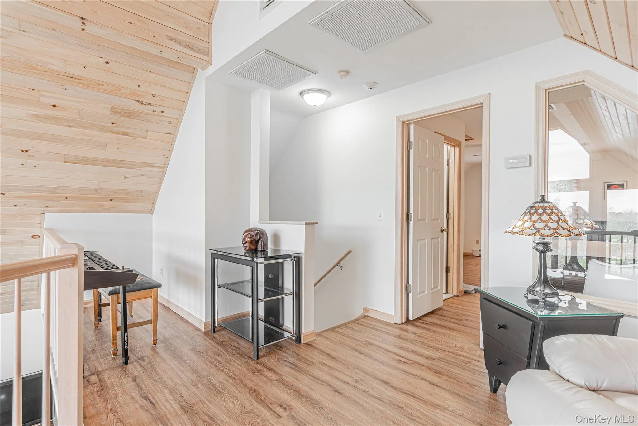Hallway featuring an upstairs landing, light wood-type flooring, vaulted ceiling, and wooden ceiling Hallway featuring an upstairs landing, light wood-type flooring, vaulted ceiling, and wooden ceiling