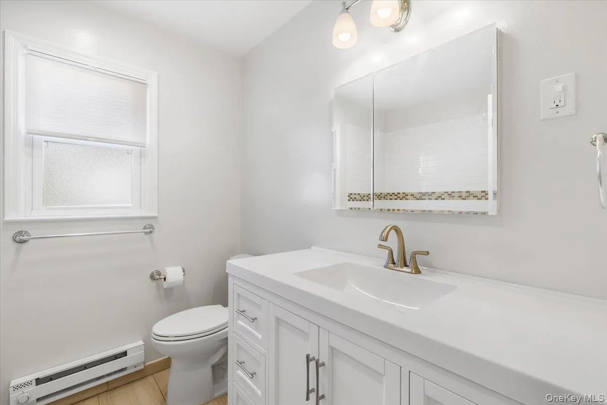 Full bath featuring a baseboard radiator and vanity. Full bath featuring a baseboard radiator and vanity.