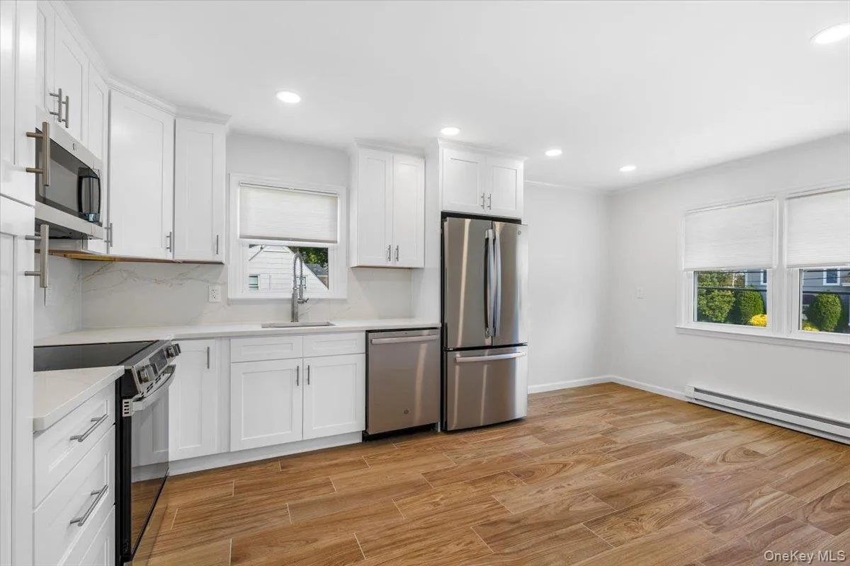 Kitchen view from entrance. Features stainless steel appliances, white cabinetry, recessed lighting. Kitchen view from entrance. Features stainless steel appliances, white cabinetry, recessed lighting.