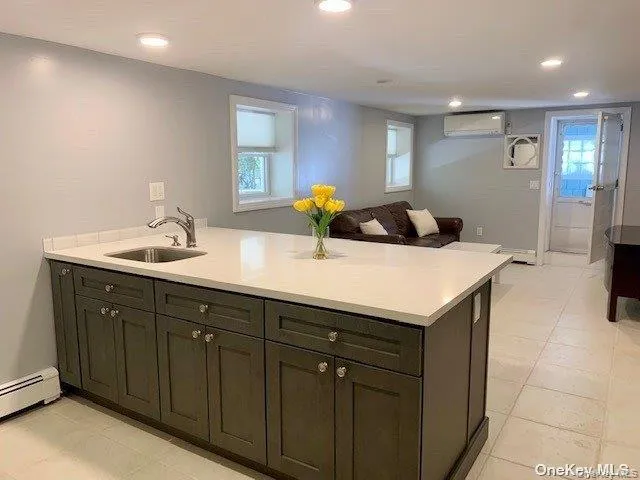 Kitchen with a peninsula, open floor plan, recessed lighting, light tile patterned flooring, and a wall mounted air conditioner Kitchen with a peninsula, open floor plan, recessed lighting, light tile patterned flooring, and a wall mounted air conditioner