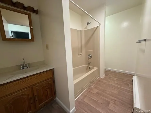 Full bath featuring shower & tub. combination, dark wood-style floors, and vanity Full bath featuring shower & tub. combination, dark wood-style floors, and vanity