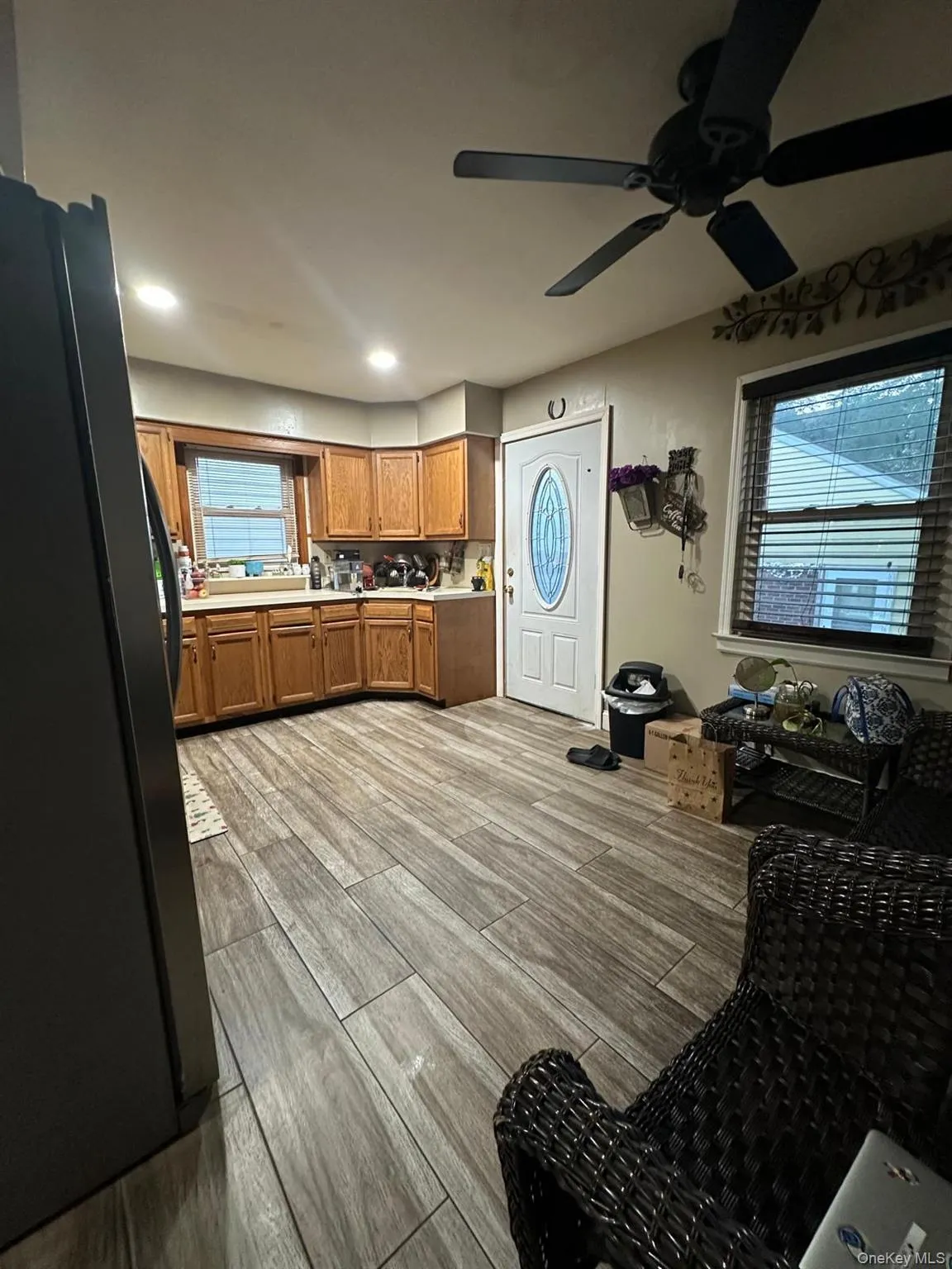 Kitchen featuring brown cabinets, light countertops, freestanding refrigerator, light wood-style floors, and healthy amount of natural light Kitchen featuring brown cabinets, light countertops, freestanding refrigerator, light wood-style floors, and healthy amount of natural light