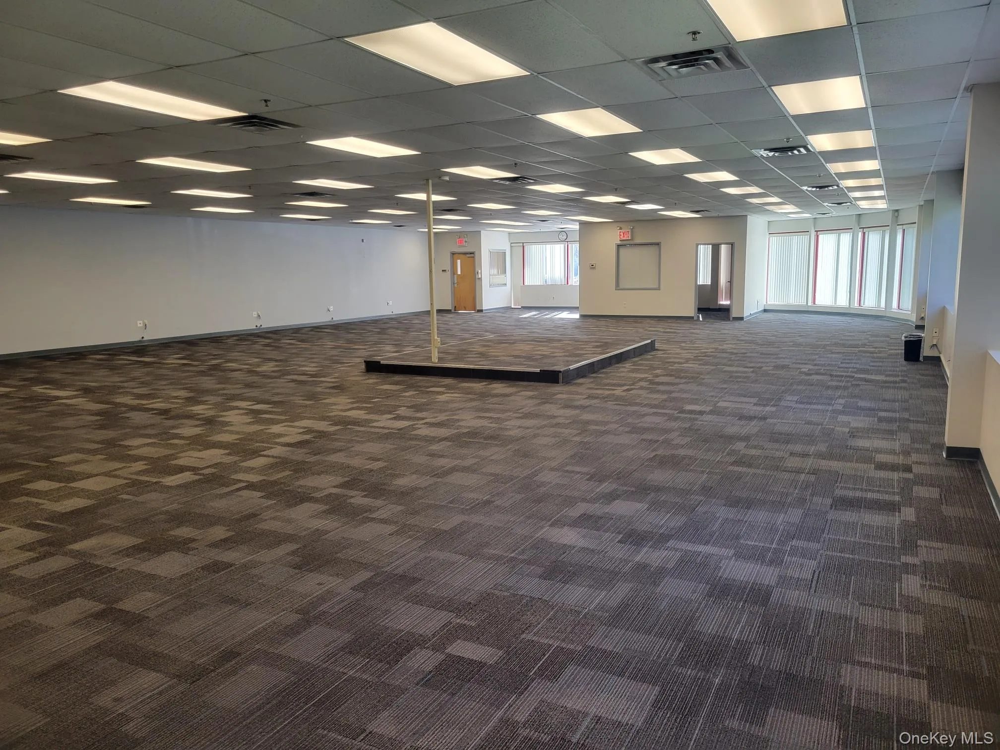 Empty room featuring dark colored carpet and a paneled ceiling Empty room featuring dark colored carpet and a paneled ceiling
