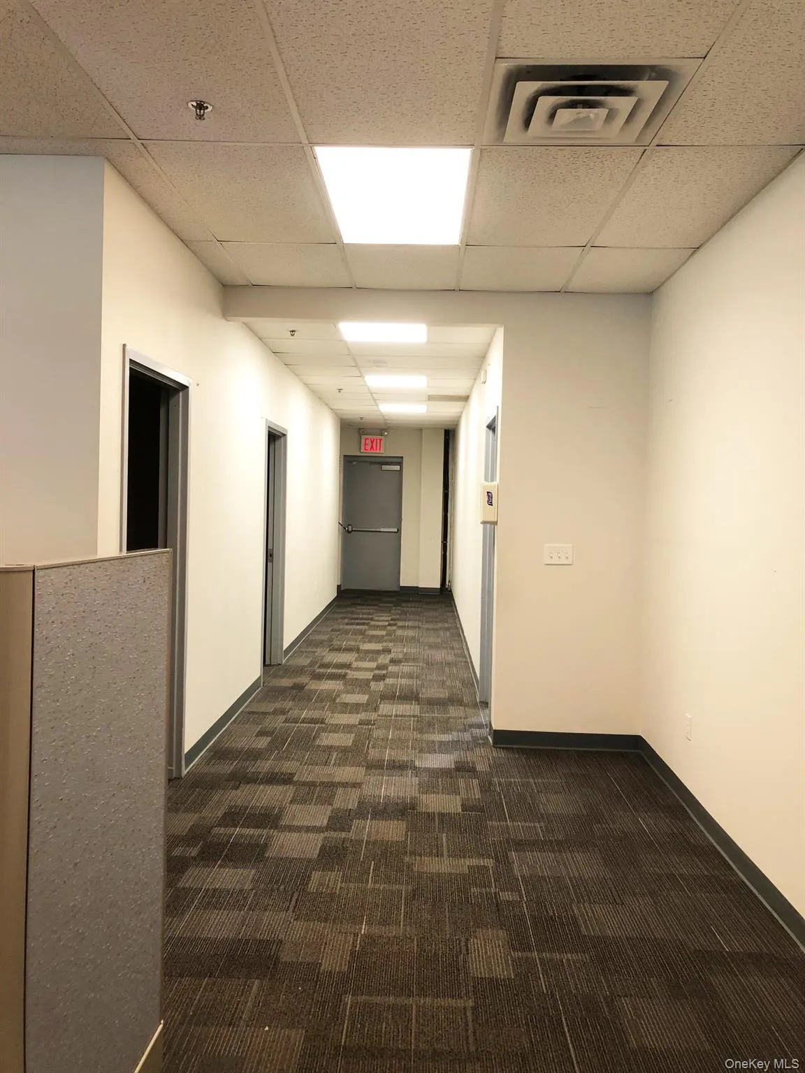 Corridor featuring dark carpet and a paneled ceiling Corridor featuring dark carpet and a paneled ceiling