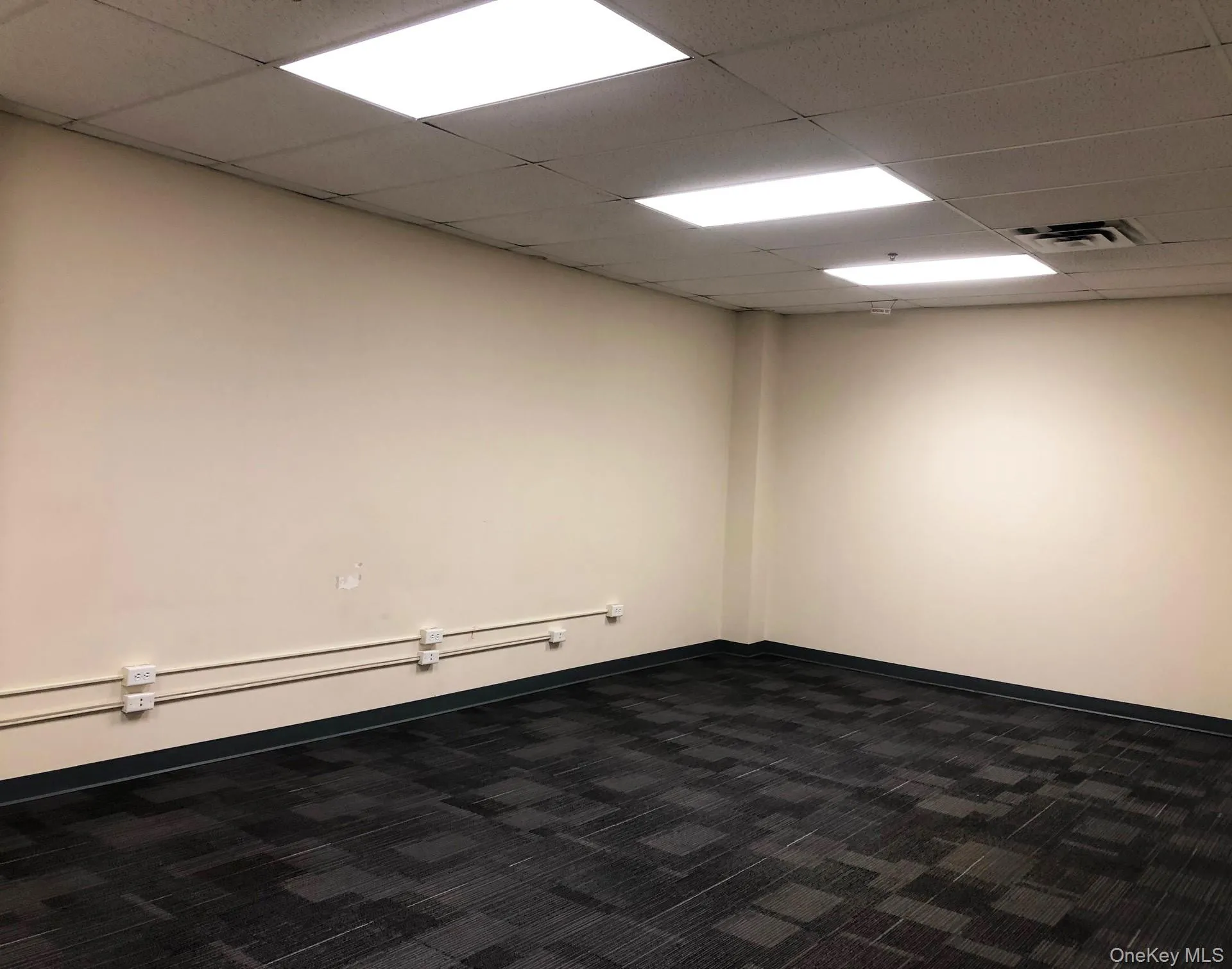 Unfurnished room featuring dark colored carpet and a drop ceiling Unfurnished room featuring dark colored carpet and a drop ceiling