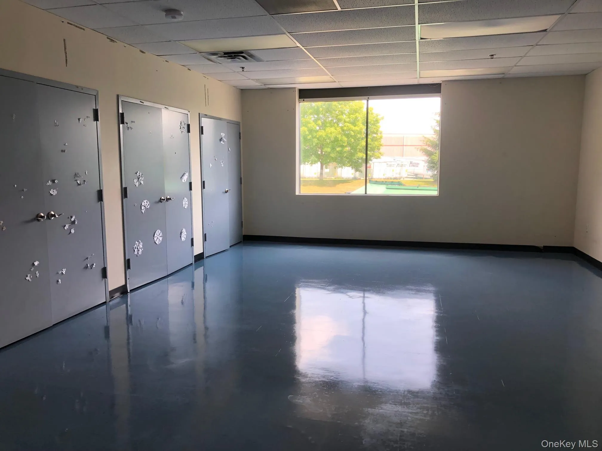Empty room with concrete flooring and a paneled ceiling Empty room with concrete flooring and a paneled ceiling