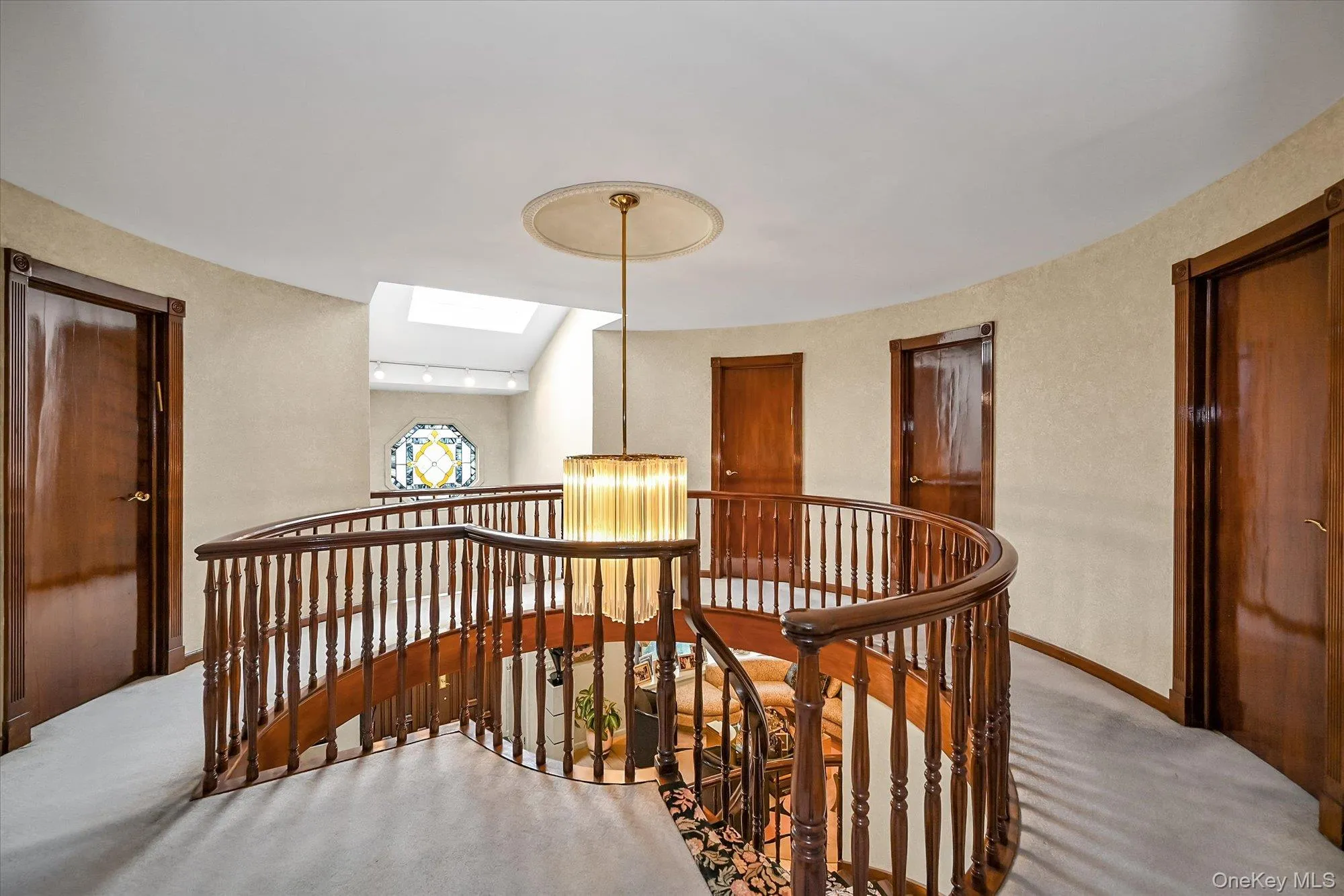 Hallway with a skylight, an upstairs landing, carpet floors, and a chandelier Hallway with a skylight, an upstairs landing, carpet floors, and a chandelier