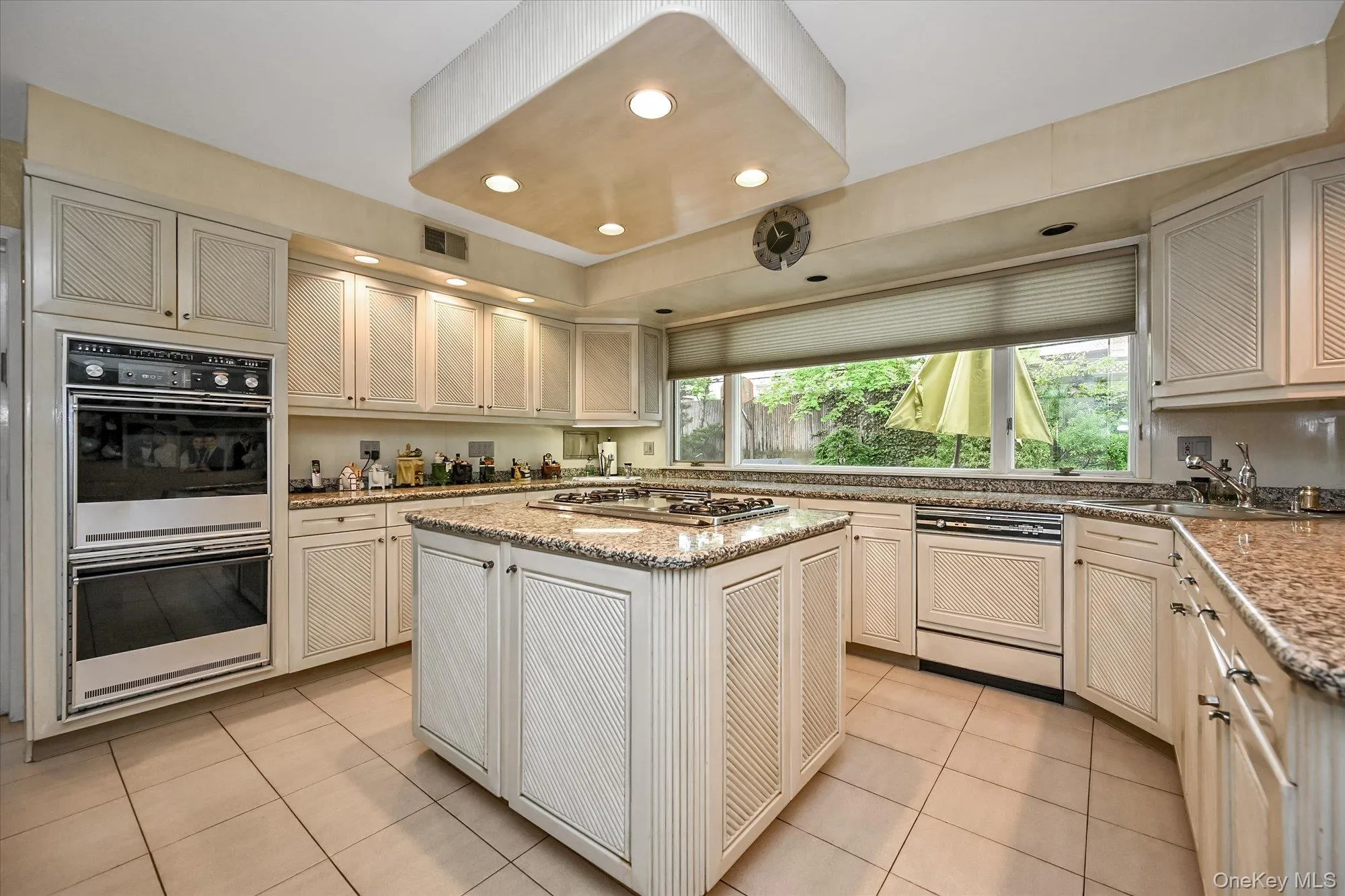 Kitchen featuring light tile patterned floors, recessed lighting, stainless steel appliances, a kitchen island, and light stone counters Kitchen featuring light tile patterned floors, recessed lighting, stainless steel appliances, a kitchen island, and light stone counters