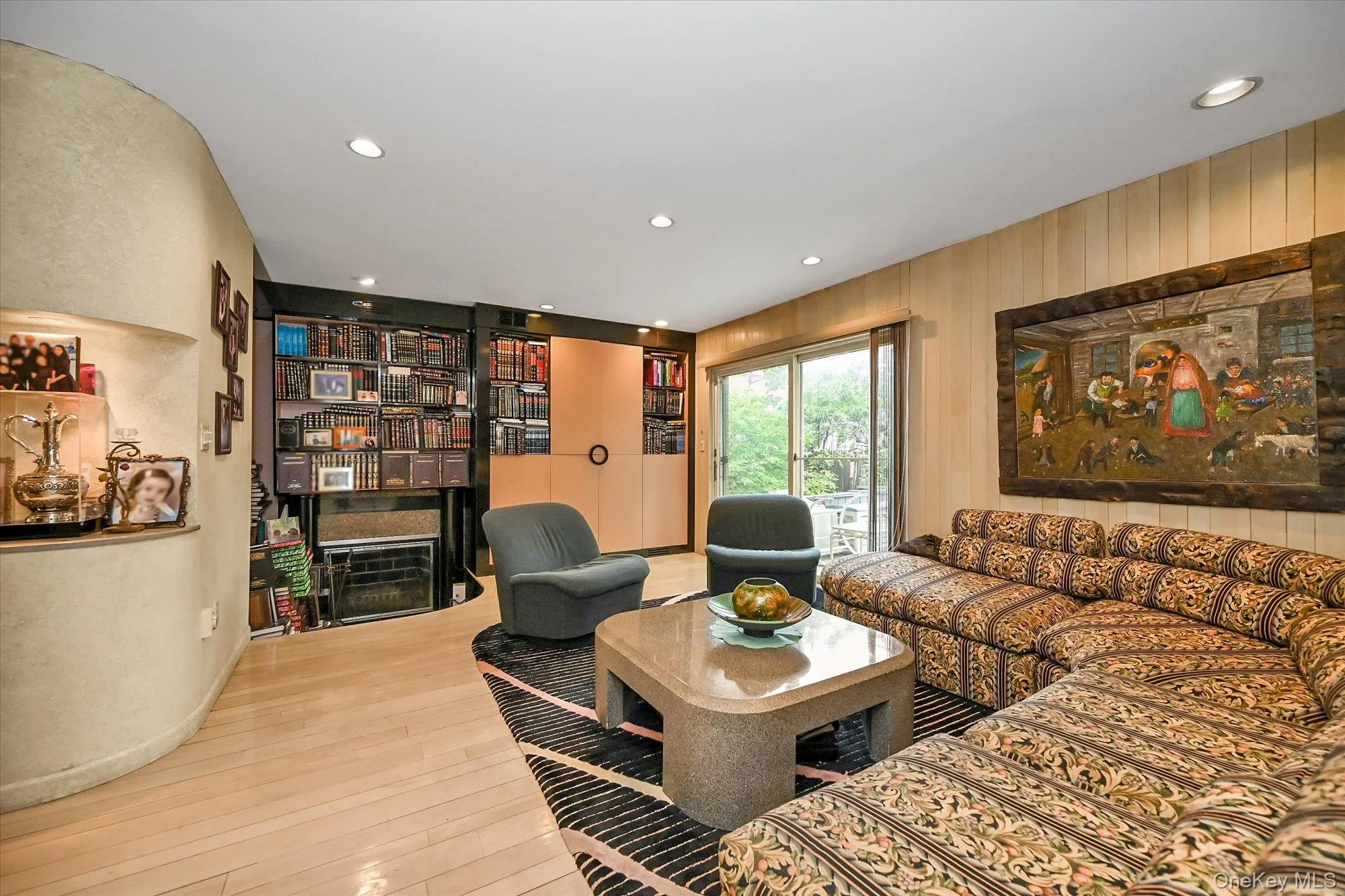 Living room with recessed lighting, light wood-style flooring, and wooden walls Living room with recessed lighting, light wood-style flooring, and wooden walls