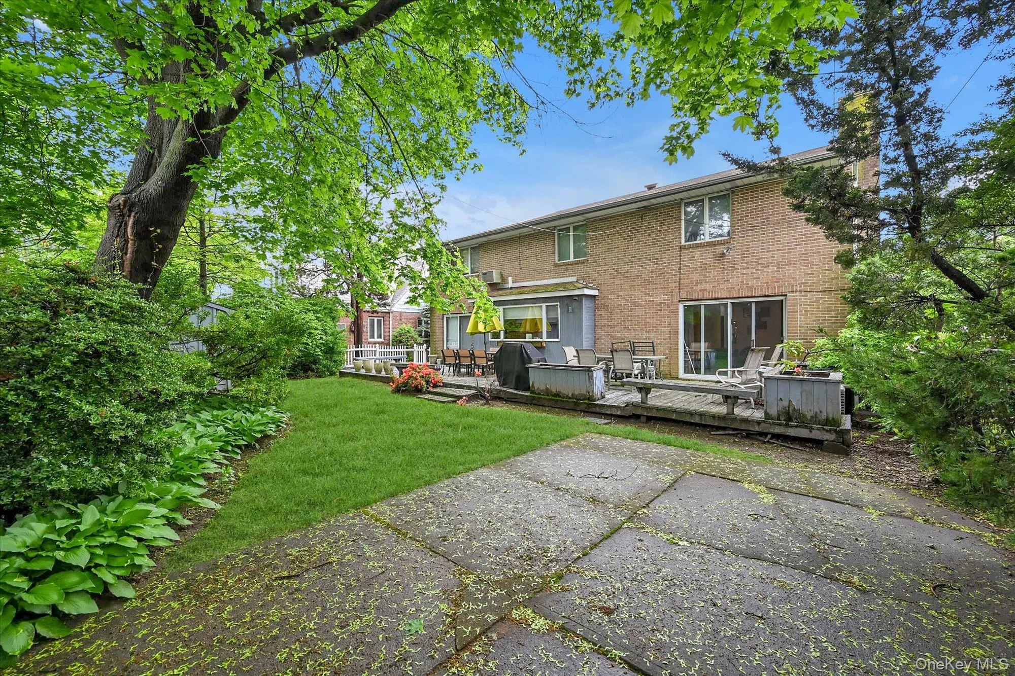 Rear view of house with a deck, brick siding, a yard, and a chimney Rear view of house with a deck, brick siding, a yard, and a chimney