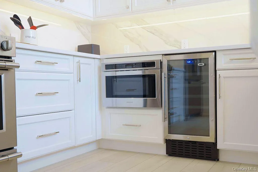 Kitchen view of white cabinetry, beverage cooler, and stainless steel microwave Kitchen view of white cabinetry, beverage cooler, and stainless steel microwave