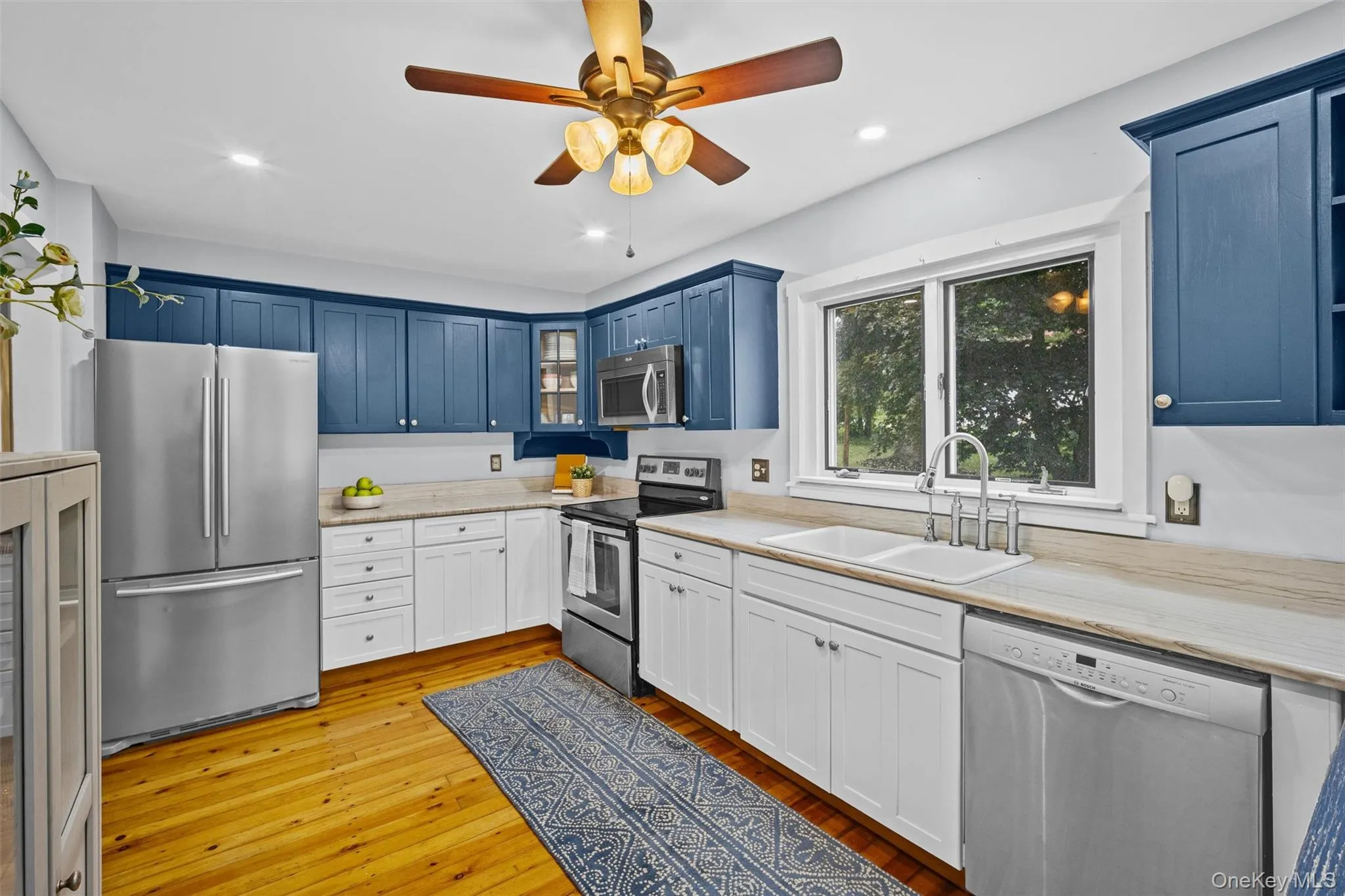 Kitchen with stainless steel appliances, light countertops, blue cabinetry, glass insert cabinets, and recessed lighting Kitchen with stainless steel appliances, light countertops, blue cabinetry, glass insert cabinets, and recessed lighting